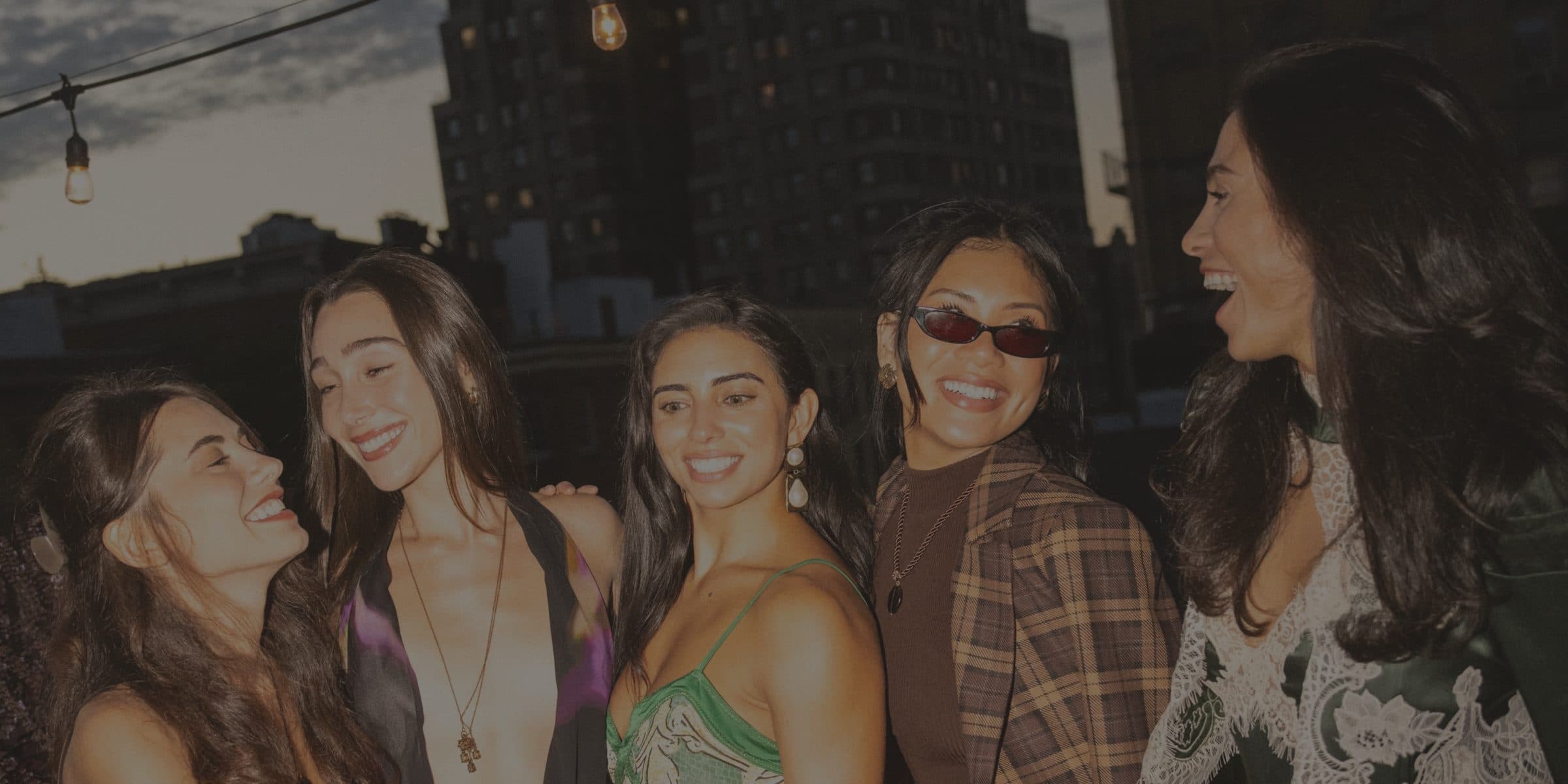 Friends laughing together on a rooftop at dusk during a Mostest event