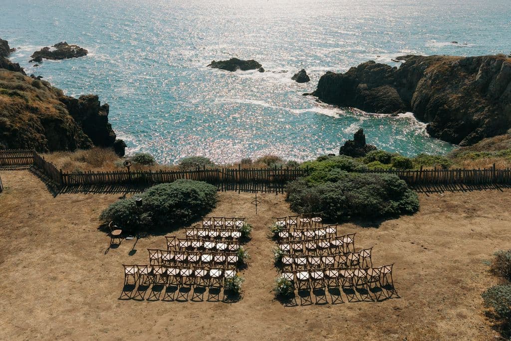Rows of chairs set for a ceremony on a clifftop above the ocean