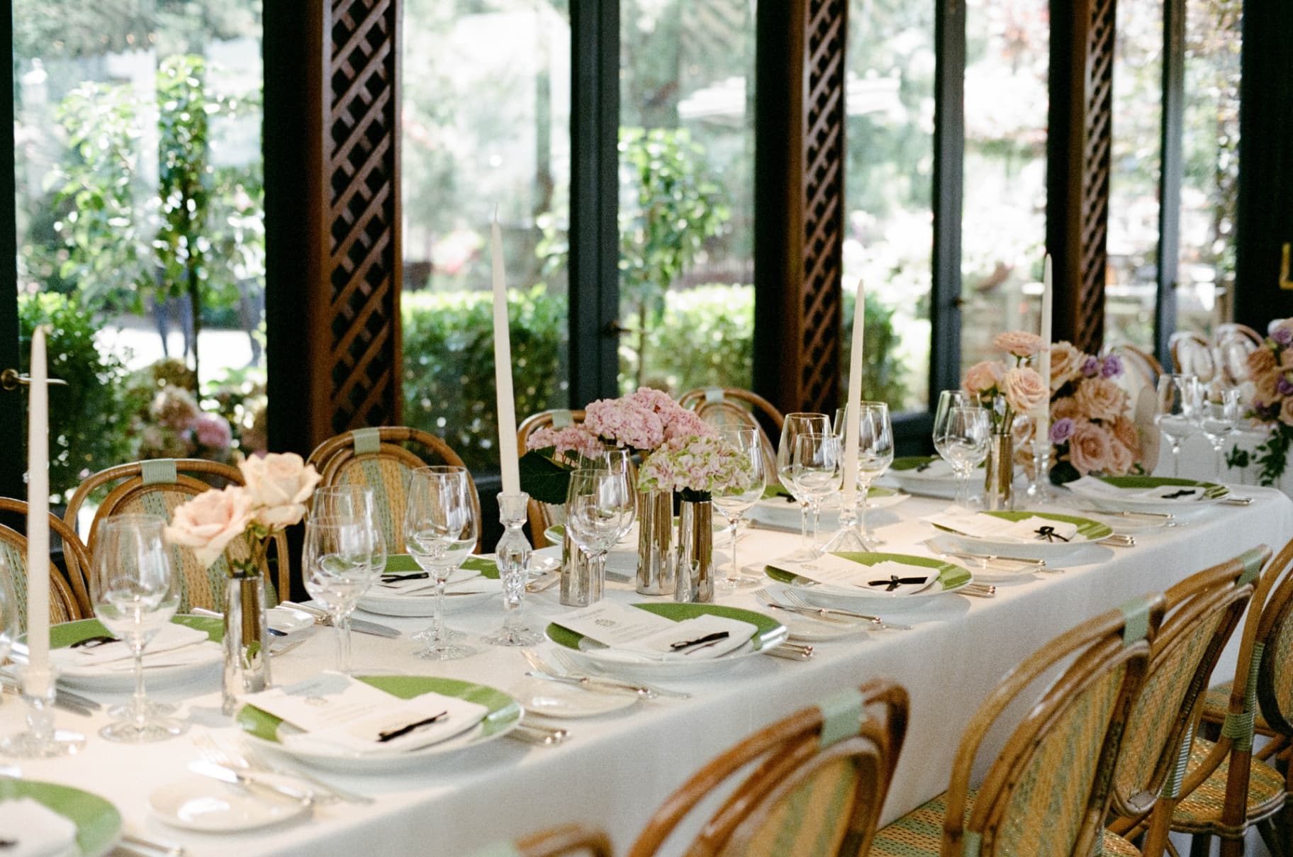 Elegant wedding reception table with green-rimmed china, taper candles, and garden florals
